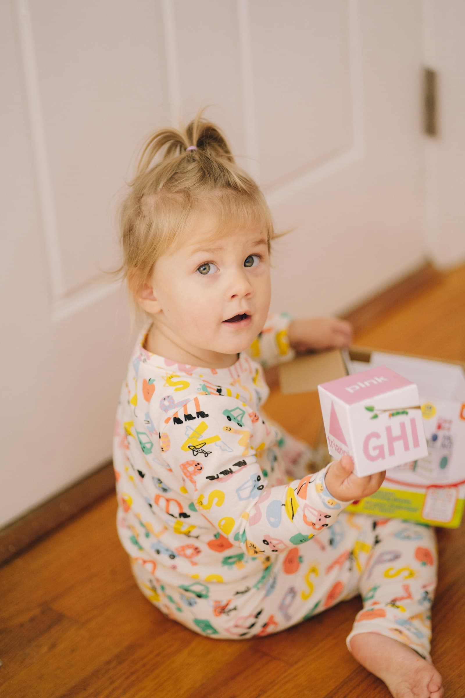 A toddler sitting on the floor holding a toy