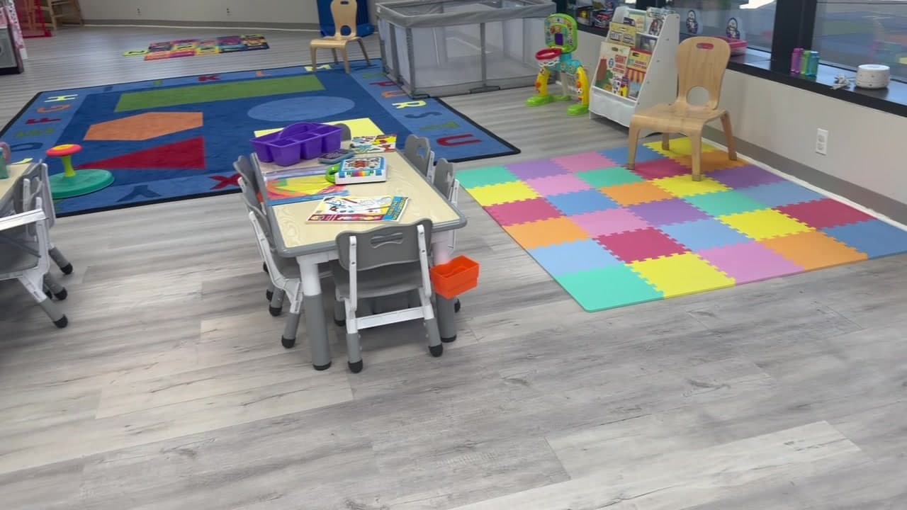 Tables, chairs and a colorful rug in a K+3 classroom
