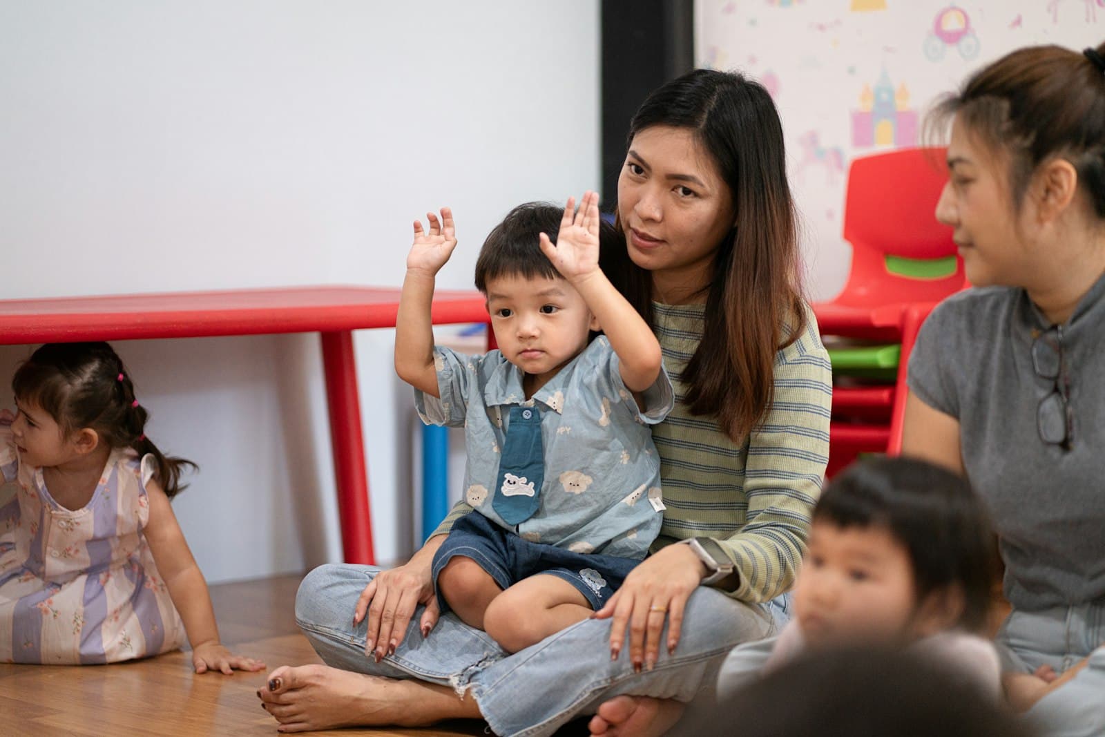 A teacher sitting on the floor with young children in a classroom