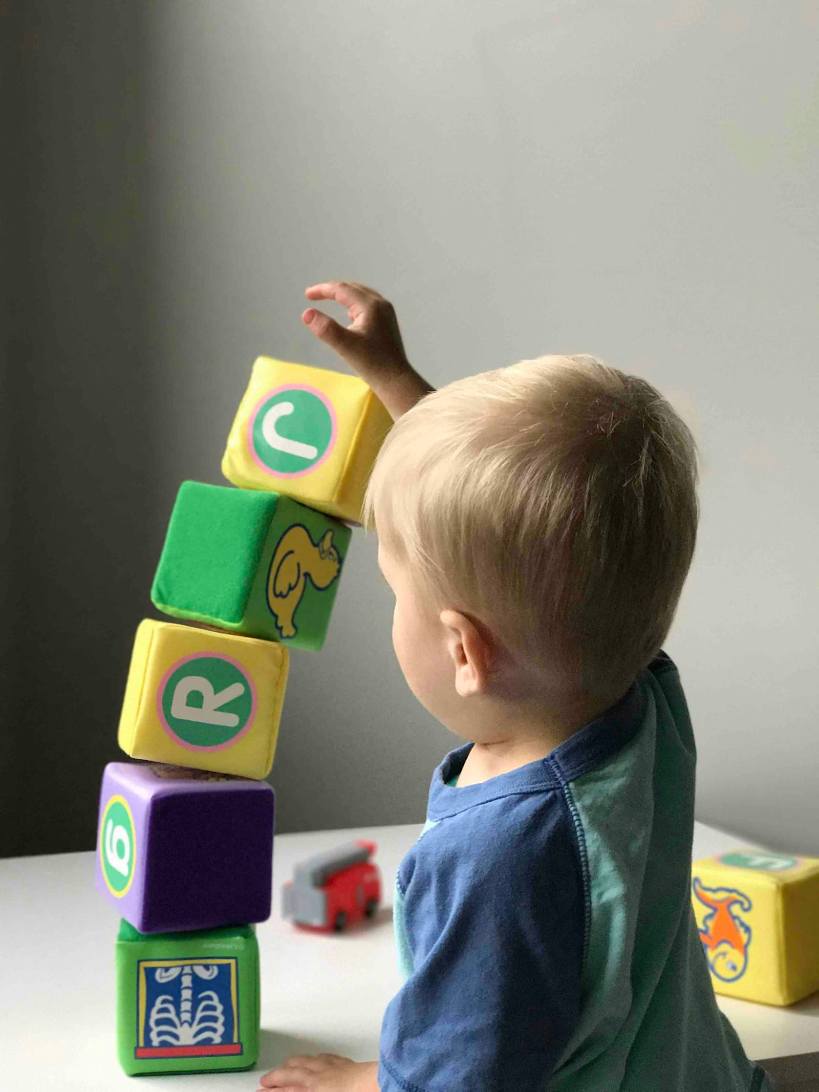 A toddler stacking colorful cubes on a table