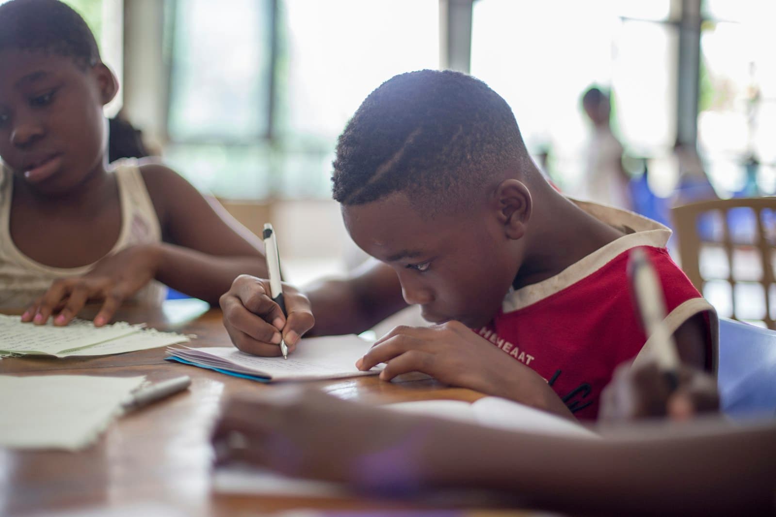 Two school age children writing at a table together