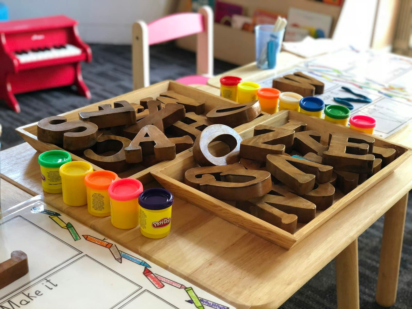 Wooden letters and play dough on a tray